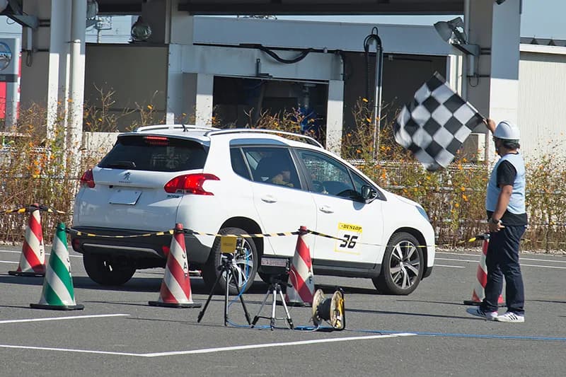オートテストのゴールシーン。係員がチェッカーフラッグを振り、パイロンで区切られたコースを車両が通過する様子