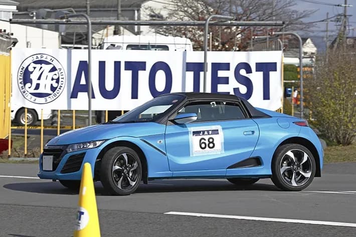JAFオートテストの競技風景。ホンダS660が「AUTO TEST」の看板前でパイロンをよけながらコースを走行する様子